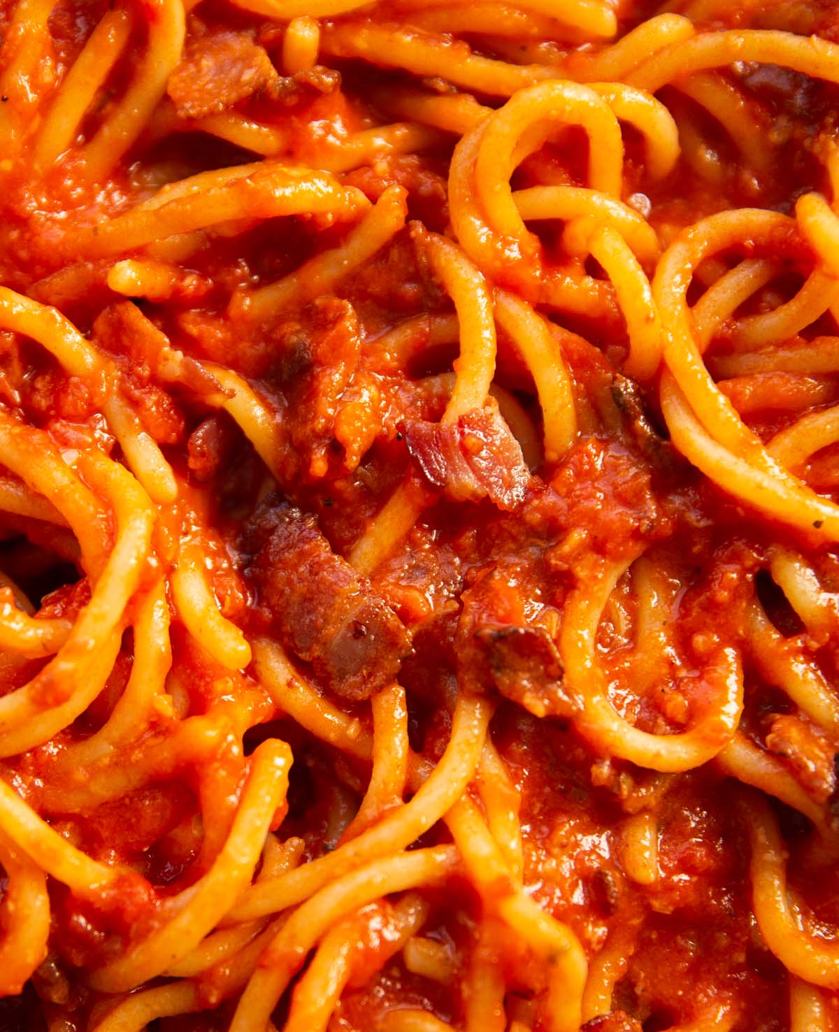 close up overhead shot of tomato bacon pasta in pan